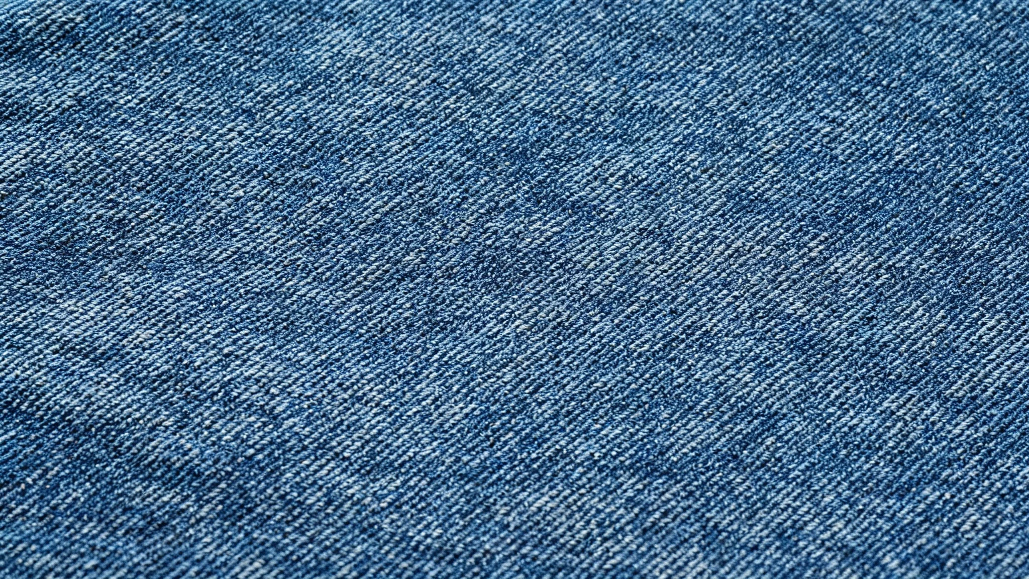 A close-up, high-resolution image of a seamless blue denim texture, showing the detailed weave and fabric threads that tile perfectly.