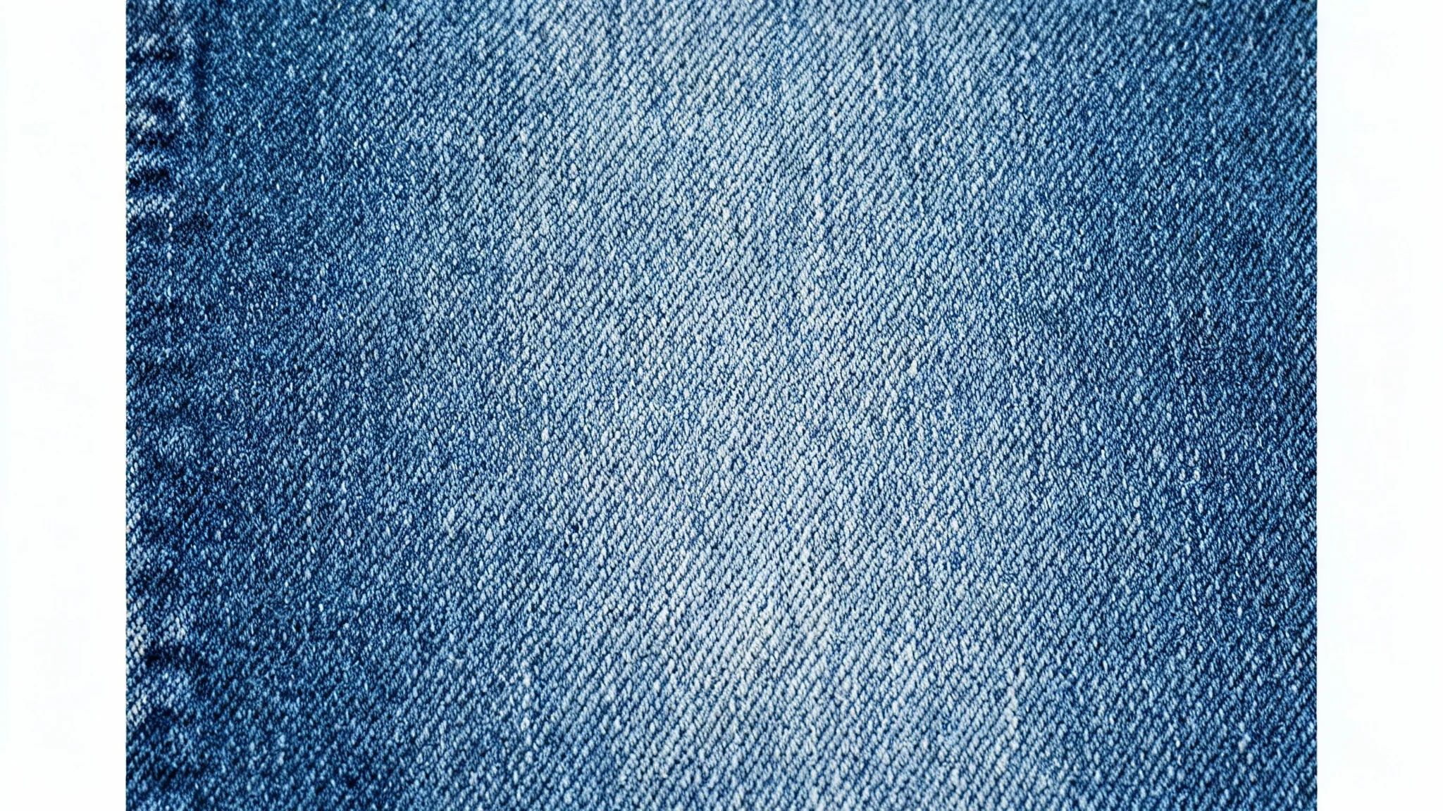 A high-resolution, top-down macro photograph of a seamless blue denim fabric, showcasing its detailed diagonal weave and the texture of its indigo and white threads.