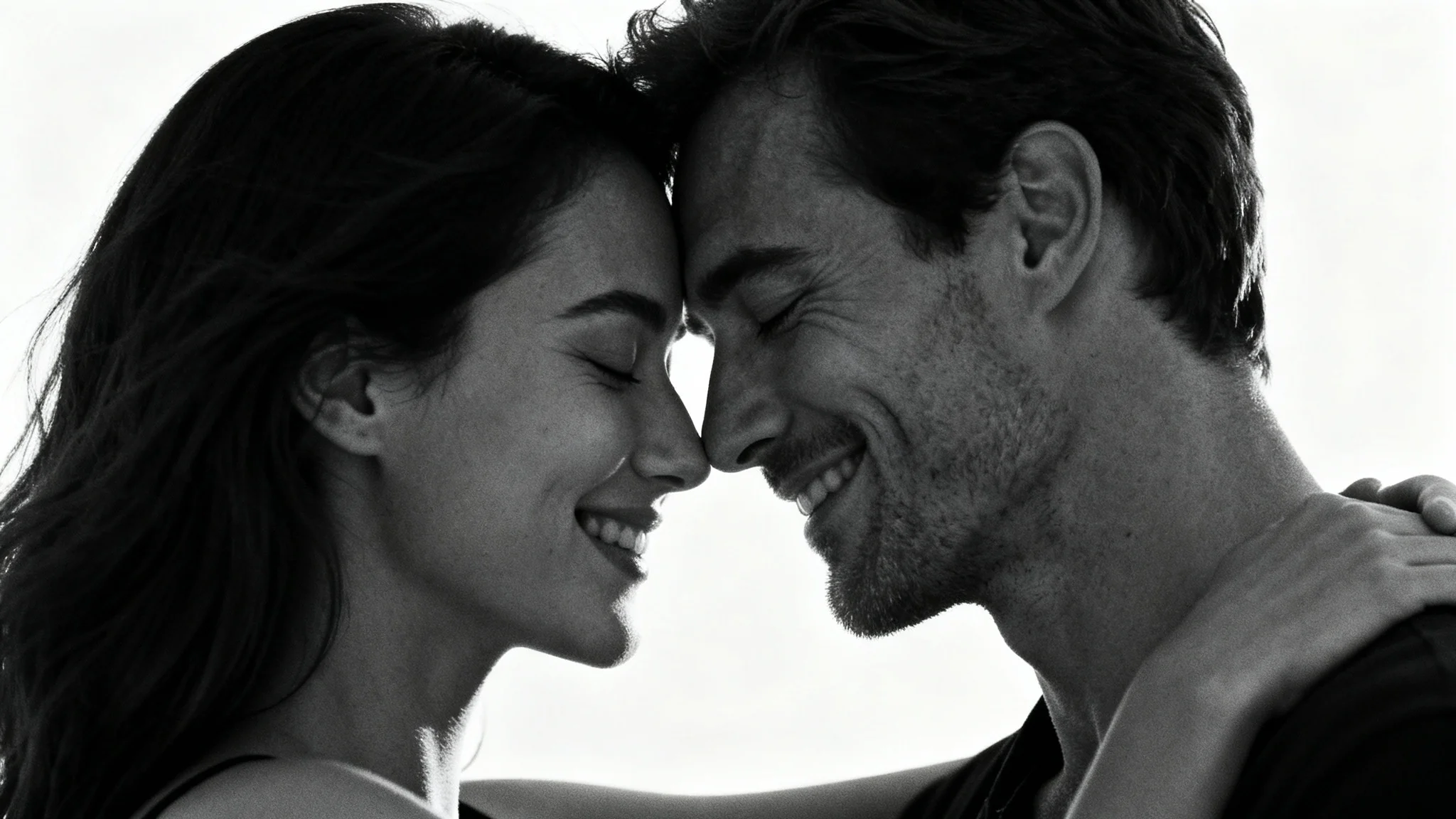 A romantic black and white photograph of a couple in a loving embrace with their foreheads touching, against a plain white background.