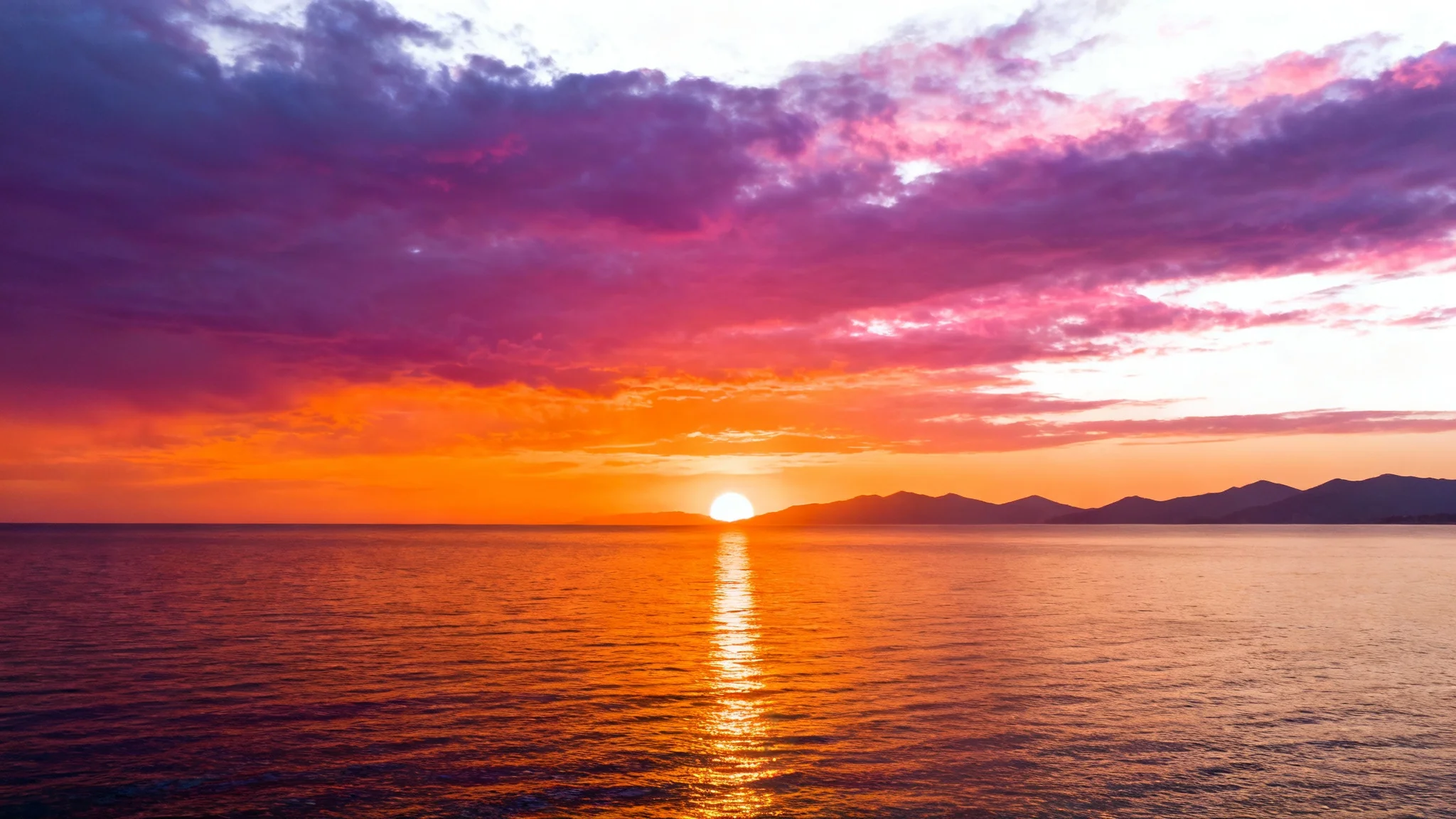 A beautiful, serene sunset over a calm ocean, with vibrant colors of orange, purple, and pink filling the sky.